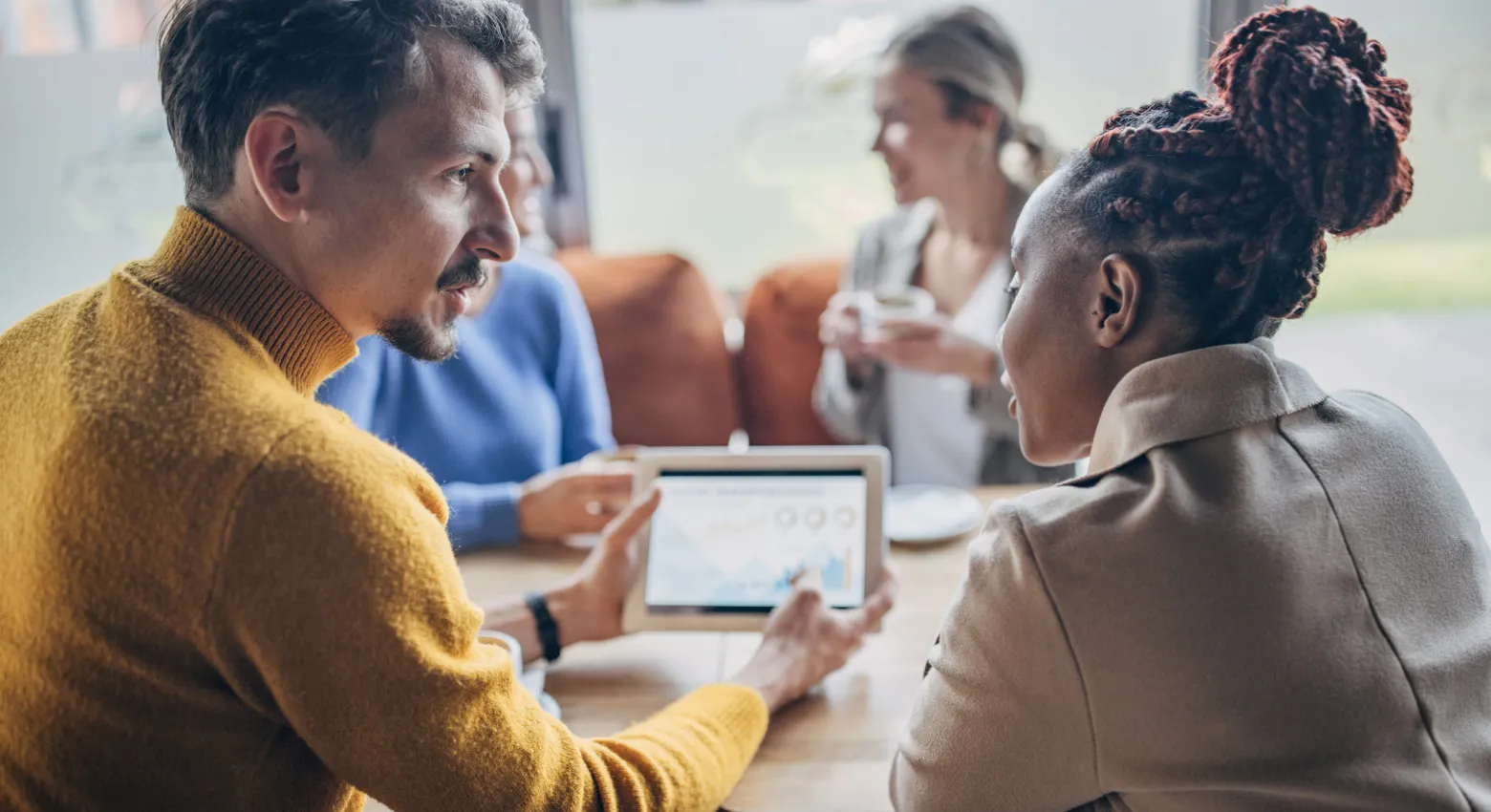 personas compartiendo una mesa con una tablet